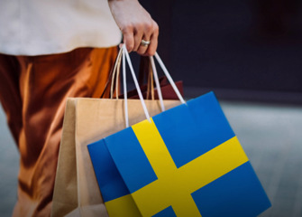 En person som bär shoppingkassar med den svenska flaggan.